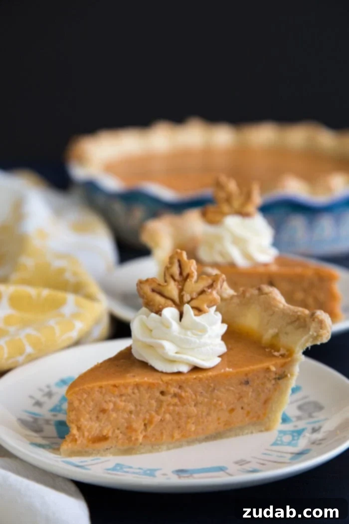 Sweet Potato Pie, made with cream cheese in the filling, a cross between a pie and a cheesecake, guaranteed to be a hit for the holidays. #sweetpotato #sweetpotatopie #sweetpotatocheesecake #holidays Generous slices of creamy sweet potato pie with cheesecake filling, beautifully presented on elegant white plates, garnished with whipped cream and a sprinkle of cinnamon, ready for a festive holiday dessert table.