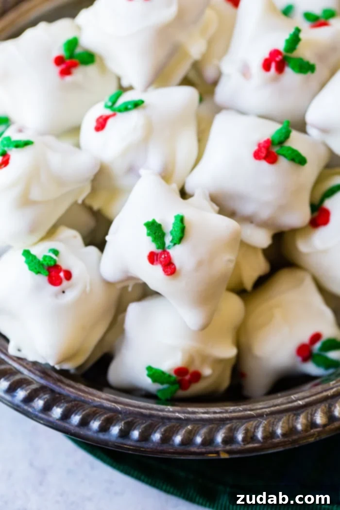 Holiday Peanut Butter White Chocolate Pretzel Crunch 4 A shiny silver bowl filled to the brim with white chocolate-dipped peanut butter pretzels, sprinkled with cheerful holly berry decorations, a delightful Christmas snack.