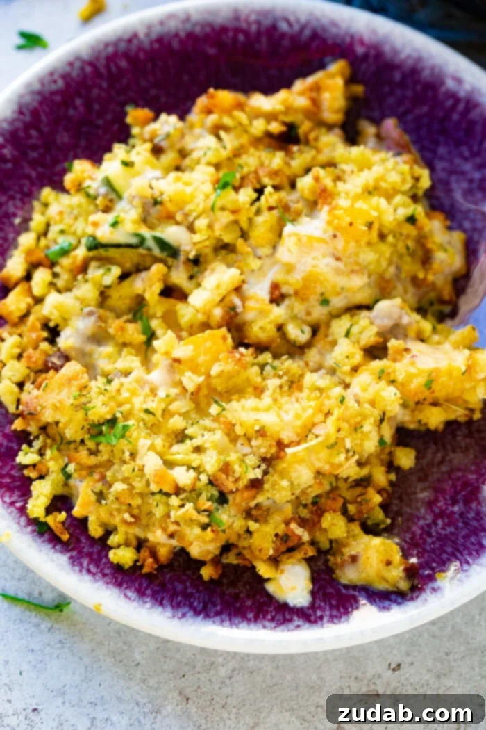 Hearty Creamy Zucchini Sausage Bake 4 A vibrant serving of creamy zucchini sausage casserole, generously topped with stuffing, nestled in a beautiful purple bowl, highlighting its inviting and comforting appeal.