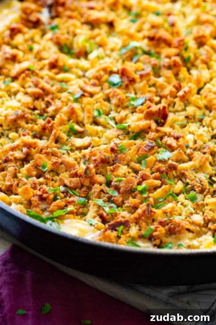 Hearty Creamy Zucchini Sausage Bake 5 A close-up shot of a creamy zucchini sausage casserole bubbling in a cast iron skillet, blanketed with a perfectly golden and toasty stuffing topping, ready to be enjoyed.