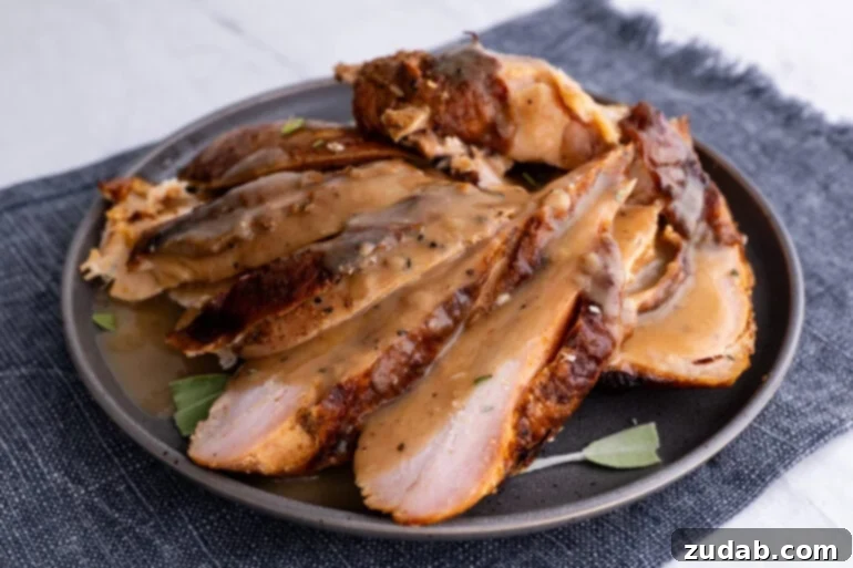 Perfectly sliced apple pecan smoked turkey breast on a dark gray plate, ready to serve.