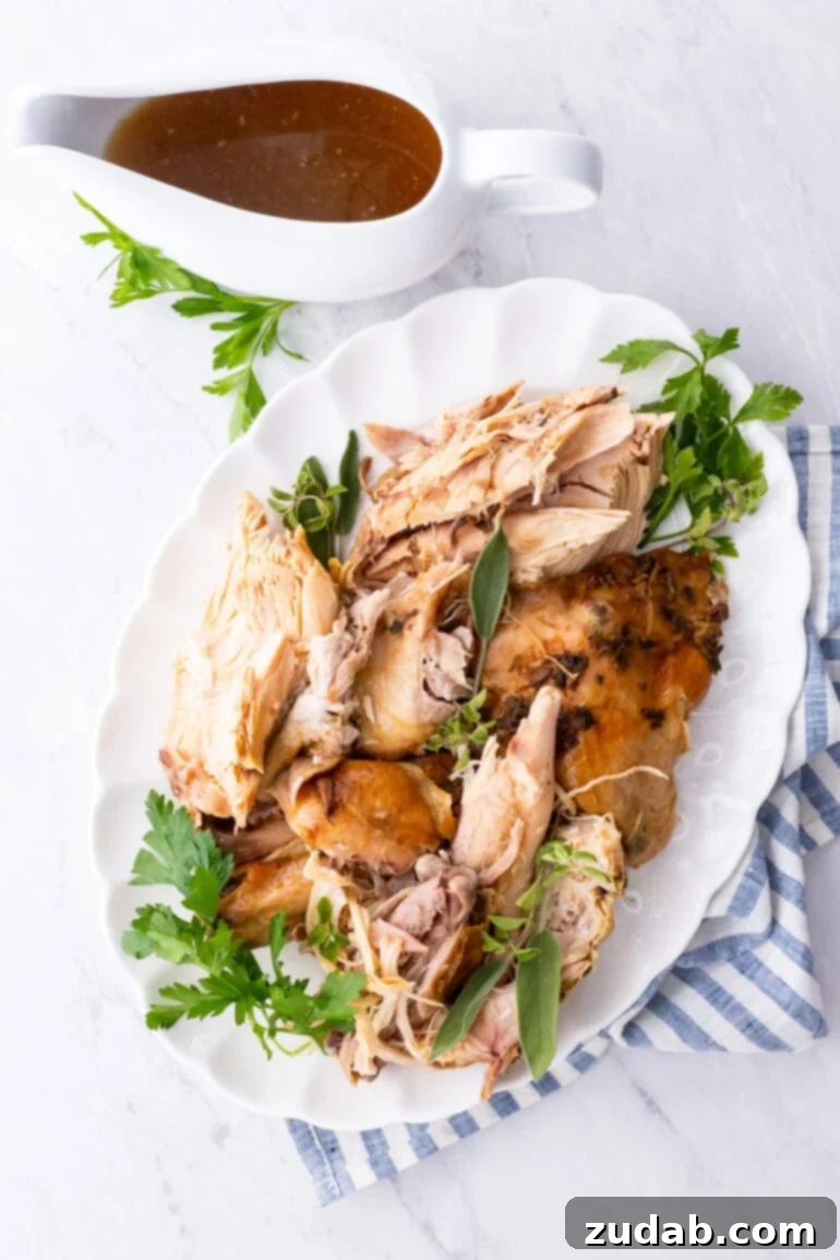 A large oval white platter laden with tender, juicy sliced turkey, accompanied by a small container of rich homemade gravy, ready to be served.