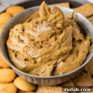 Creamy Gingerbread Delight 4 A close-up of creamy Gingerbread Cookie Dip in a small bowl, garnished with a gingerbread cookie, with graham crackers and Nilla wafers for dipping.