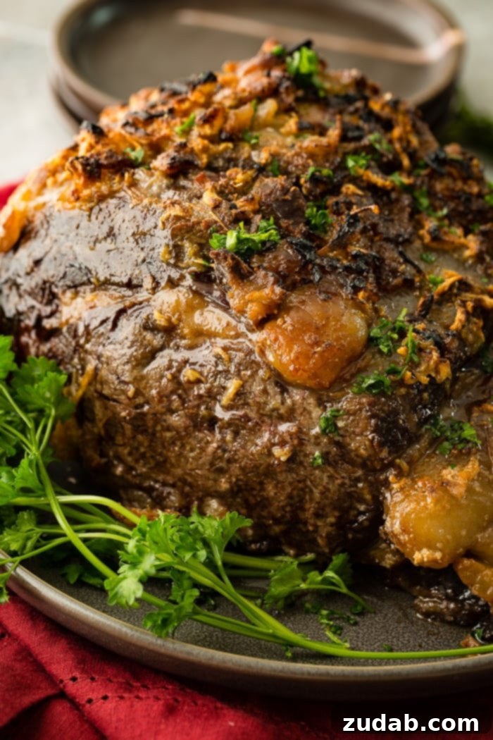 The Ultimate Prime Rib Recipe 2 Garlic herb crusted prime rib roast on a platter, ready for carving