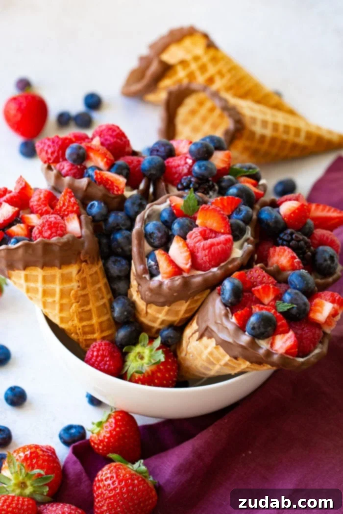 Waffle Cone Fruit Yogurt Parfaits 3 A bowl of waffle cones filled with yogurt, strawberries, blueberries & raspberries with 2 waffle cones in the background.