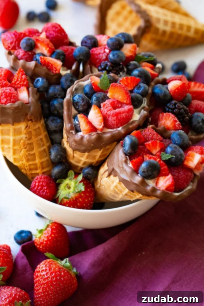 Waffle Cone Fruit Yogurt Parfaits 7 A white bowl filled with waffle cone fruit and yogurt cups with a purple linen and more berries.