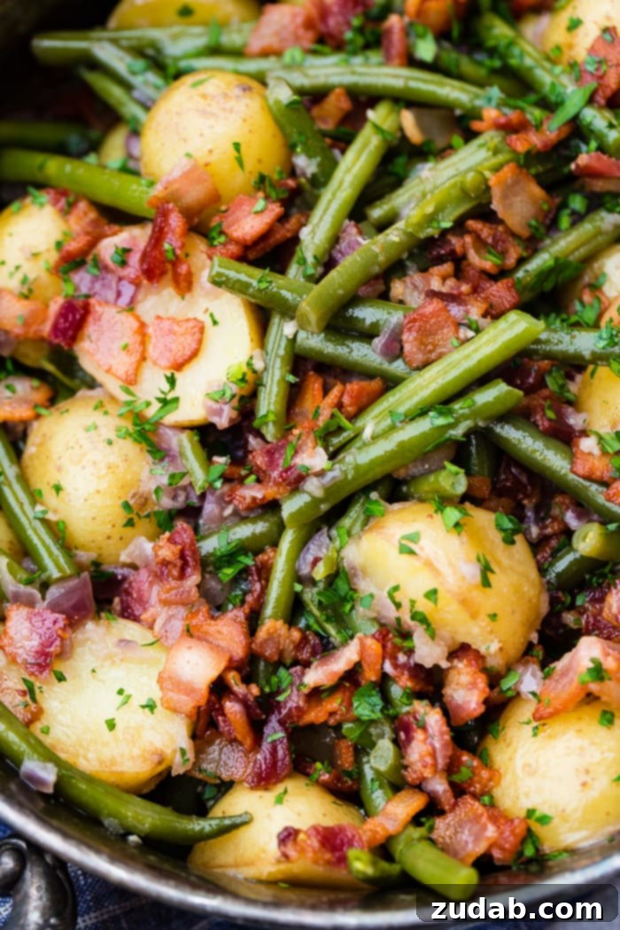 Effortless Instant Pot Green Beans and Potatoes 6 a zoomed in photo of cooked green beans, potatoes, and bacon pieces sprinkled with fresh parsley.