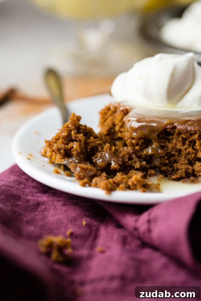 Spiced Ginger Cake with Zesty Lemon Glaze 3 Close-up of a warm gingerbread cake with a generous drizzle of lemon sauce and a dollop of white whipped cream, inviting a taste of festive comfort.