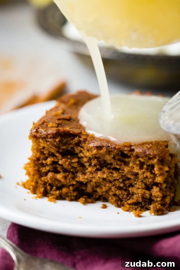 Spiced Ginger Cake with Zesty Lemon Glaze 4 A perfectly portioned slice of warm gingerbread cake, adorned with glistening lemon sauce and a delicate dollop of whipped cream, ready to be enjoyed.