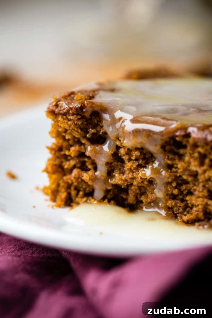 Spiced Ginger Cake with Zesty Lemon Glaze 6 A slice of warm gingerbread cake, beautifully presented with a generous swirl of lemon sauce and a peak of whipped cream, inviting indulgence.