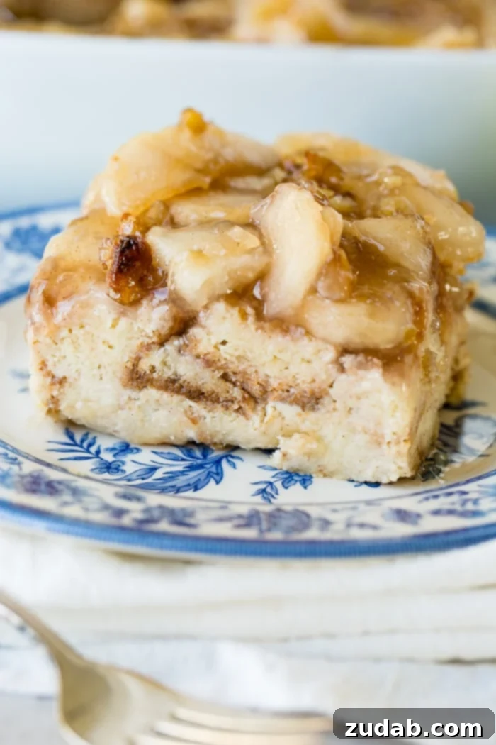 Warm Apple Pie Bread Pudding Drizzled with Vanilla Sauce 4 a large slice of easy bread pudding with vanilla sauce sitting on a blue china plate with a bite taken out of the front.