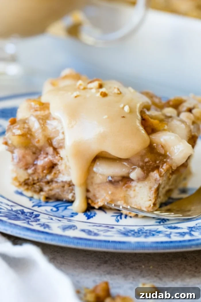 Warm Apple Pie Bread Pudding Drizzled with Vanilla Sauce 7 a large slice of apple pie bread pudding with vanilla sauce sitting on a blue china plate with a bite taken out of the front.