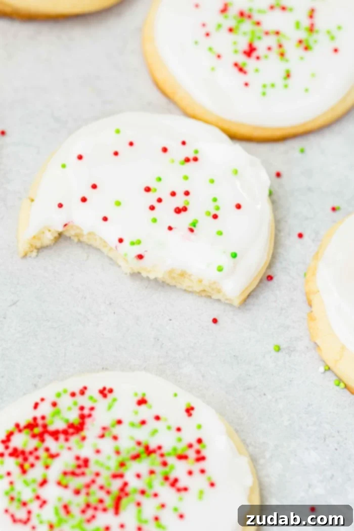Festive Peppermint White Chocolate Sugar Cookies 3 a photo of several sugar cookies with white royal icing and green and red sprinkles with one cooking having bites taking out of it