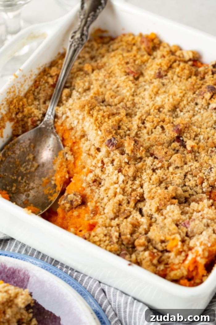 This Sweet Potato Souffle Outshines Ruths Chris 5 A generously sized, fluffy sweet potato souffle with a deeply golden brown sugar and pecan topping, baked to perfection in a white dish.