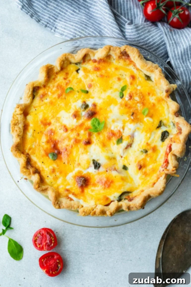 Southern Comfort in a Crust Tomato Pie 6 a photo of a whole baked tomato pie topped with melted cheese and fresh basil leaves