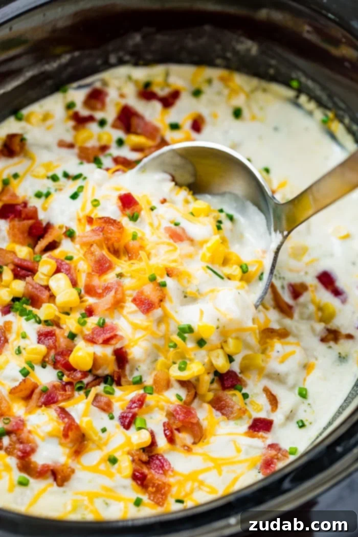 Creamy Slow Cooker Potato, Broccoli & Corn Chowder with Crispy Bacon 5 Close-up of a white bowl full of slow cooker potato broccoli corn chowder with crispy bacon and chives.