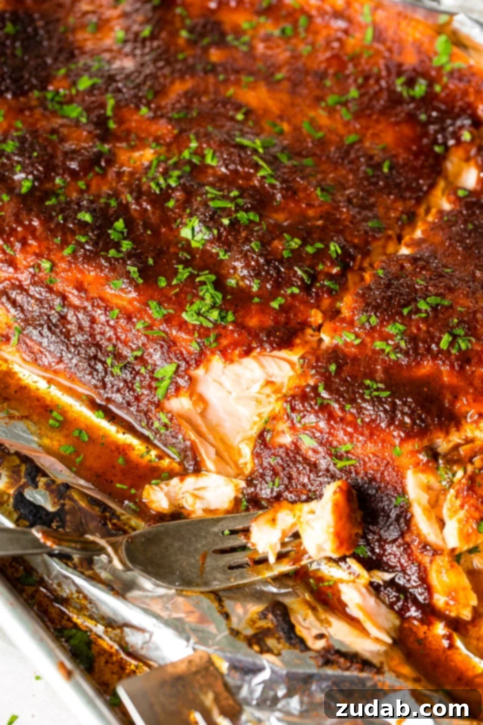 baked glazed salmon in foil with a fork resting on the side