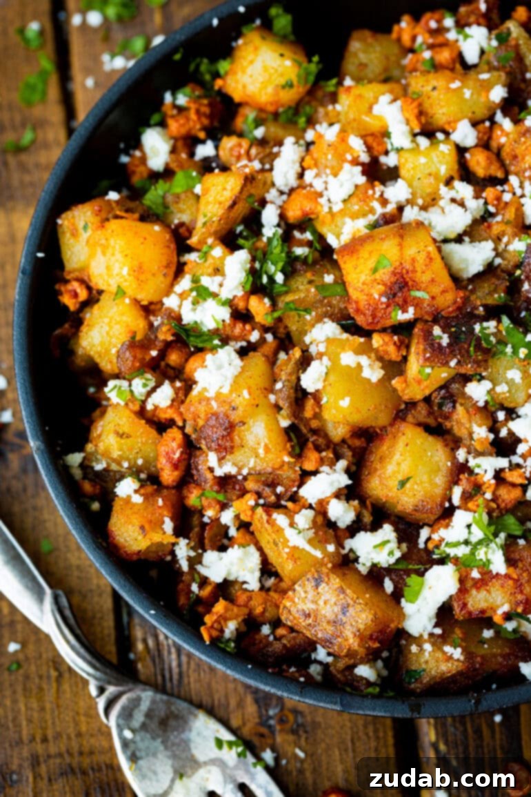 Simple Chorizo Potato Skillet 2 A large serving dish filled with golden, crispy cubed potatoes mixed with spicy chorizo, fresh cilantro, and crumbled cotija cheese, ready to be served.
