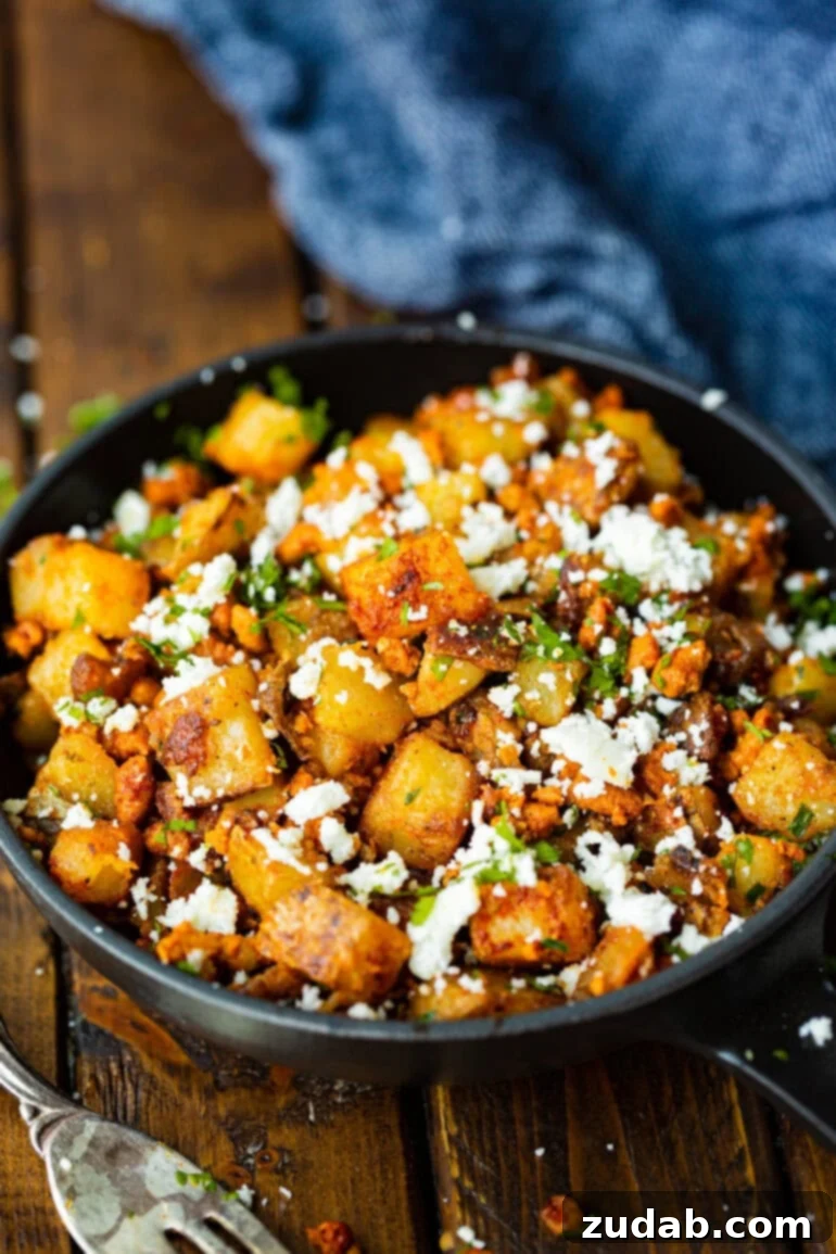 Simple Chorizo Potato Skillet 3 A large serving bowl showcasing vibrant golden, crispy potato chunks intimately mixed with rich, spicy chorizo, garnished with fresh cotija cheese and finely chopped cilantro.