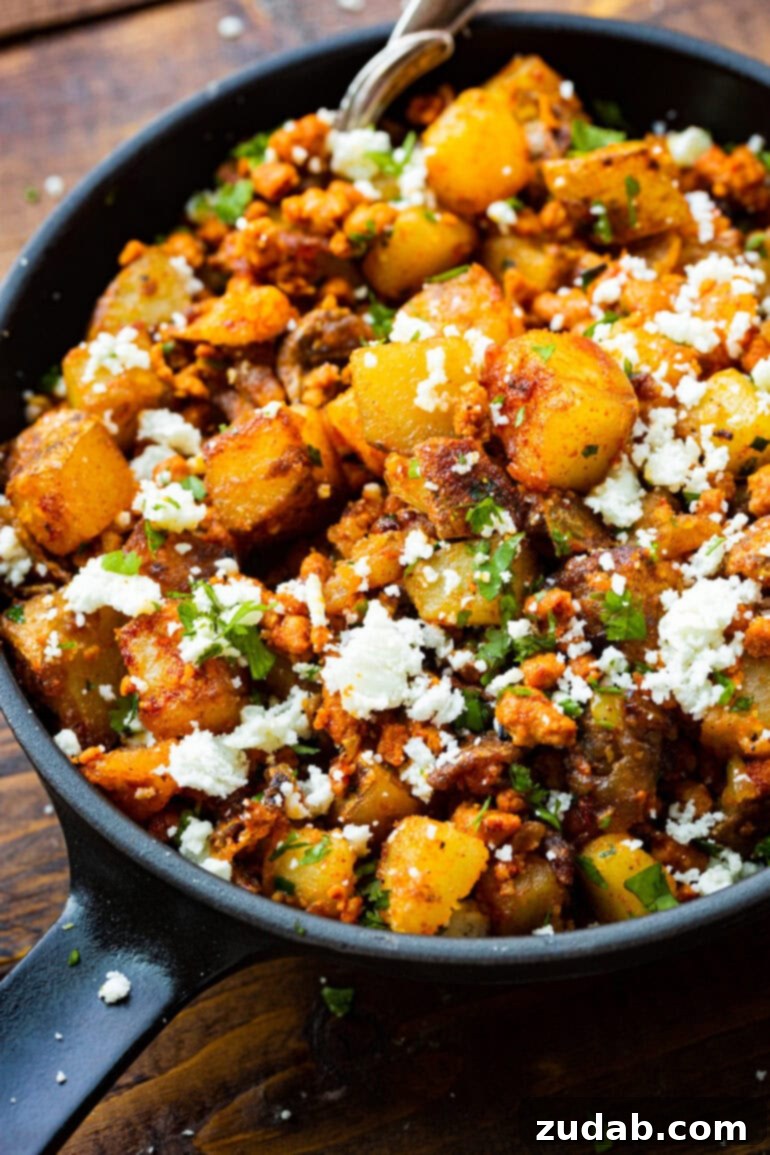 Simple Chorizo Potato Skillet 5 A close-up shot of crispy golden potatoes generously mixed with spicy chorizo, adorned with fresh cilantro and crumbles of cotija cheese, highlighting its irresistible texture.