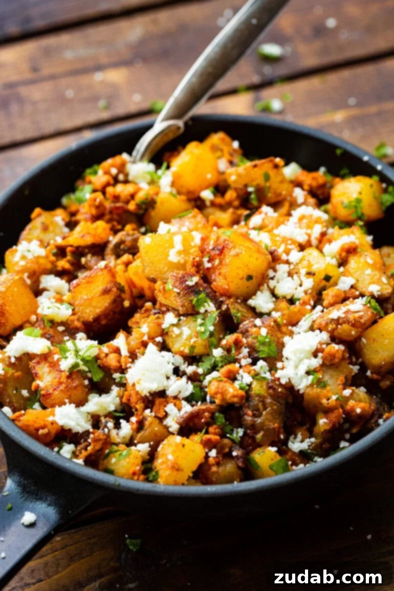 Simple Chorizo Potato Skillet 6 A vibrant bowl of easy chorizo and potatoes, adorned with fresh cilantro and a serving spoon, inviting you to dig in and enjoy.