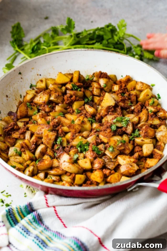Simple Chorizo Potato Skillet 8 A red and white skillet showcasing quick and easy 3-ingredient chorizo potatoes, generously topped with fresh cilantro, ready for a delicious meal.