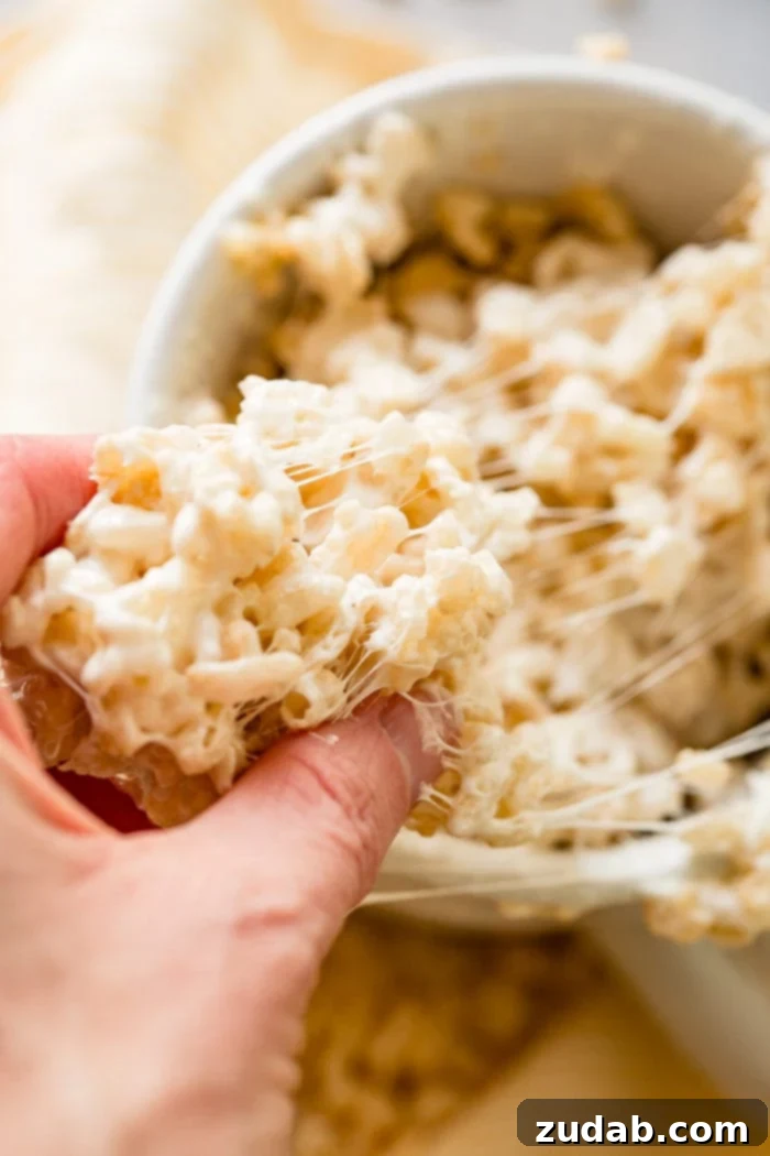 2-Minute Rice Krispie Treat in a Mug 3 A photo of a handful of rice krispies treat being pulled out of a mug full of gooey rice krispies treat.