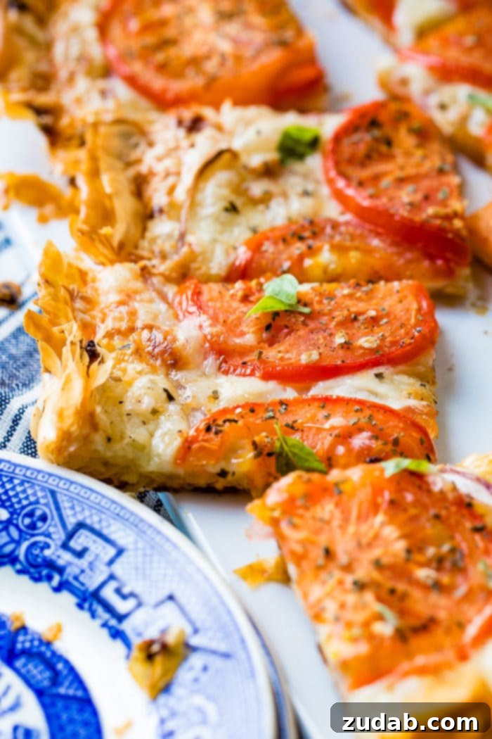 Country Tomato Galette 7 Several slices of rustic tomato tart are arranged on a white cutting board, highlighting the diverse textures and colors of the ingredients, ready for serving.