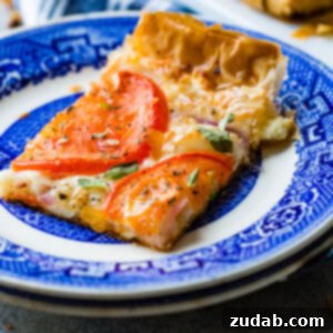 A charming close-up of a rustic tomato tart, showcasing its golden crust, vibrant tomato slices, and fresh green basil, capturing its homemade allure.