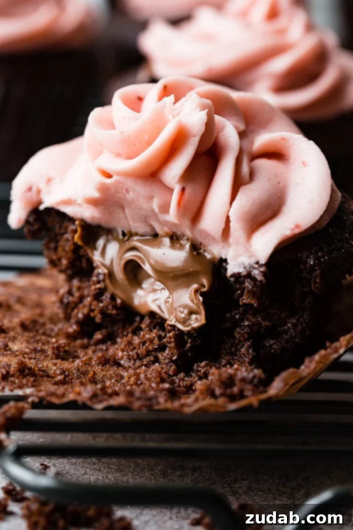 Nutella Lava Strawberry Chocolate Cupcakes 2 a close up of a nutella stuffed chocolate cupcake with strawberry buttercream frosting