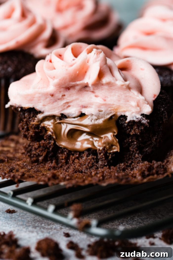 Nutella Lava Strawberry Chocolate Cupcakes 4 a close up of a nutella stuffed chocolate cupcake with strawberry buttercream frosting