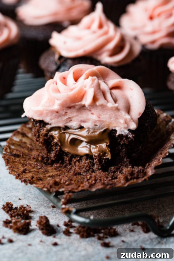 Nutella Lava Strawberry Chocolate Cupcakes 6 a close up of a nutella stuffed chocolate cupcake with strawberry buttercream frosting