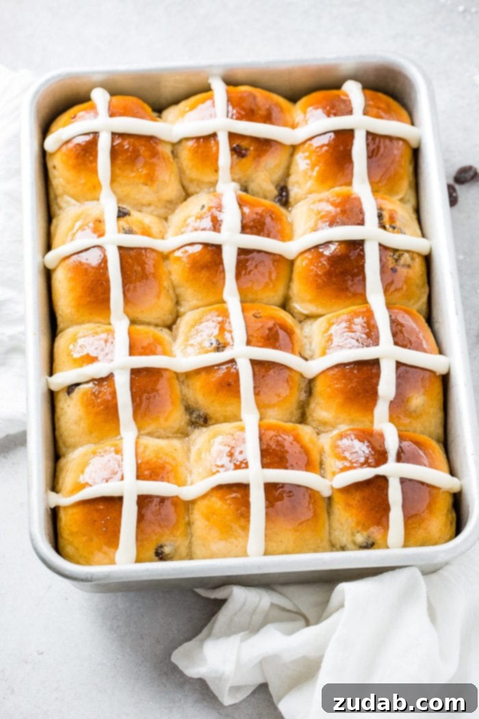 Pillowy Soft Hot Cross Buns 6 A photo looking down on a pan of hot cross buns with white frosting crosses on them.