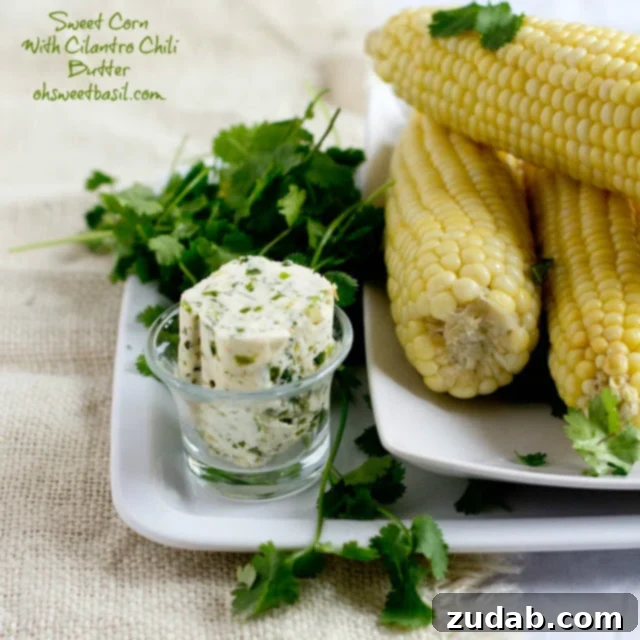 Cilantro Buttered Corn 3 Close-up of fresh cilantro butter being spread onto a cooked ear of corn, showing the vibrant green herb specks.