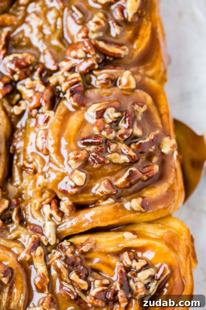 Irresistible Pecan Sticky Buns 2 A photo of a sticky bun taking from above covered in a caramel glaze and chopped pecans.