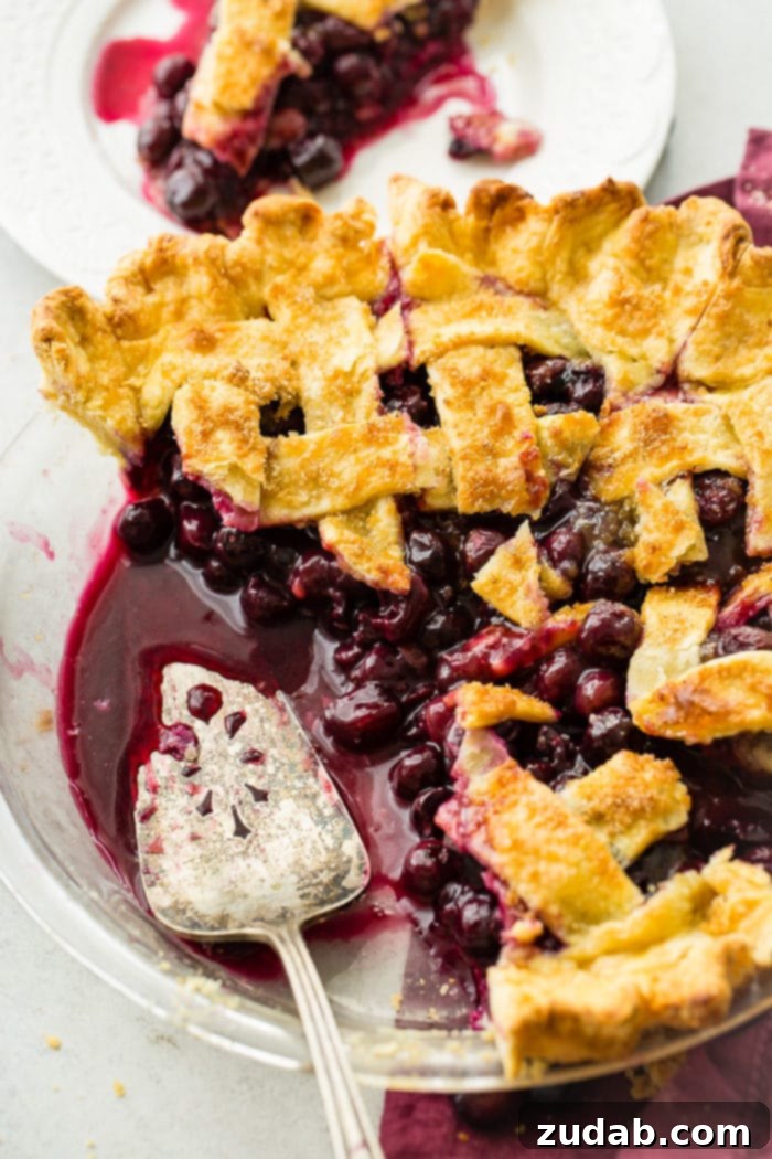 Effortless Blueberry Pie 10 A photo of a blueberry pie with a lattice top, with a couple of slices taken out and a pie server in the pan.