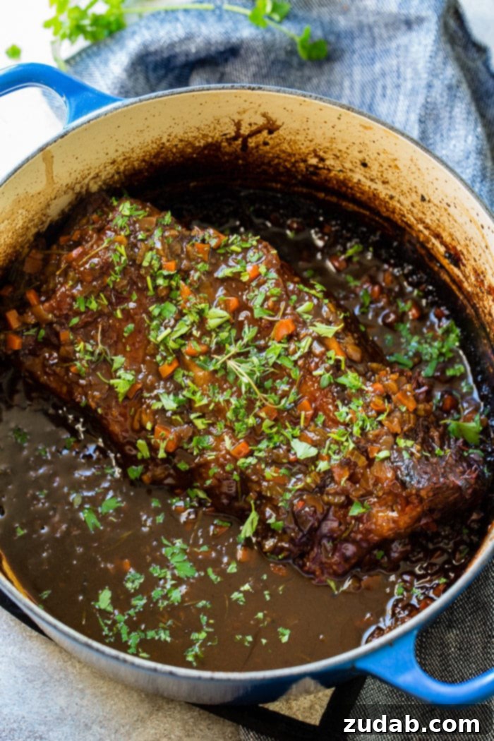 Hearty Oven-Braised Pot Roast 5 A photo of a braised chuck roast sitting in all its beautiful juices in a dutch oven pot.