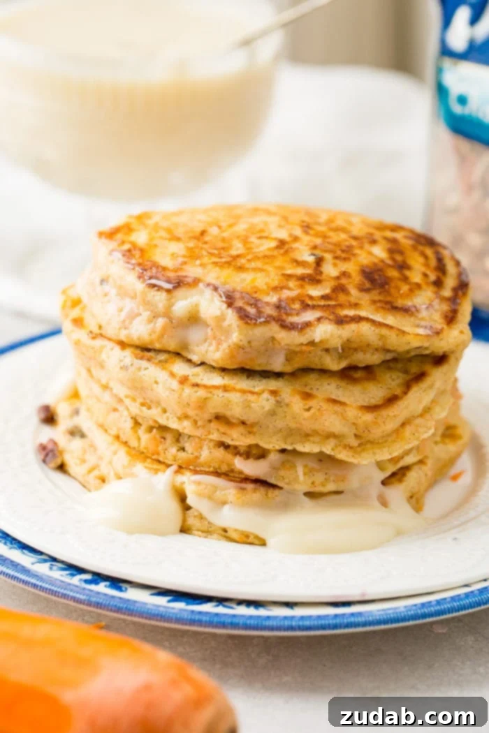 Sweet and Spiced Carrot Cake Pancakes 3 A photo of a stack of golden carrot cake pancakes on a white plate with no syrup added yet.