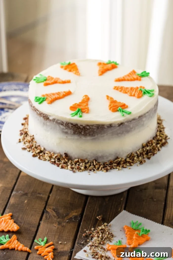 My Signature Spiced Carrot Cake 3 A two-layer carrot cake on a white cake stand, generously covered in creamy white cream cheese frosting and topped with white chocolate carrots, surrounded by chopped pecans at the base.