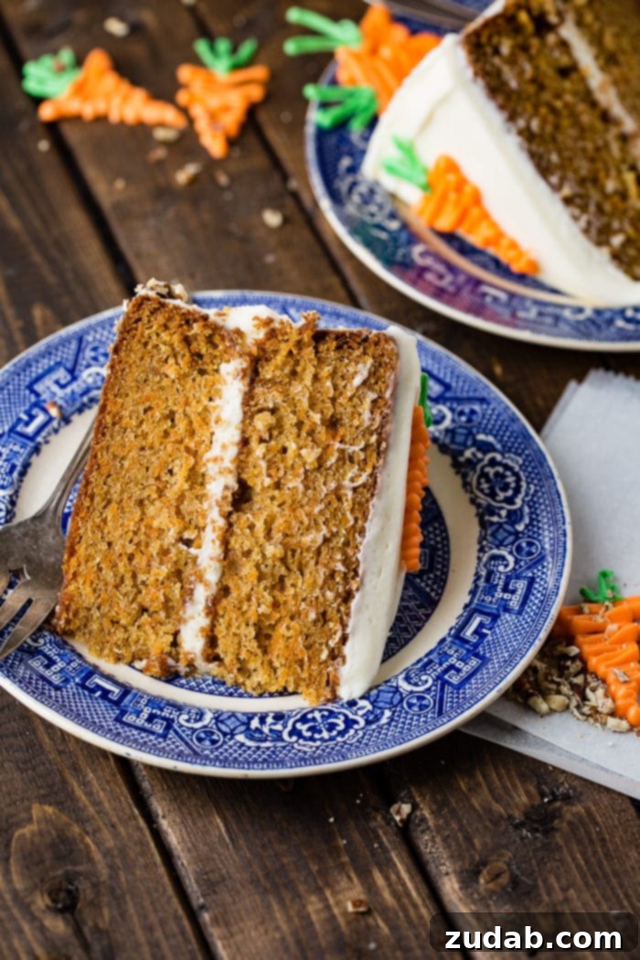 My Signature Spiced Carrot Cake 7 A charming slice of two-layer carrot cake, showcasing generous cream cheese frosting, casually positioned on a blue and white plate.