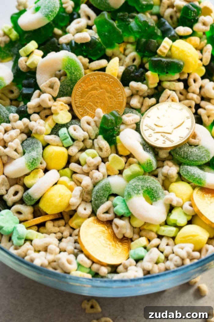 Lucky Leprechaun's 5-Minute Treat 3 Another enticing photo of the St. Patrick's Day snack mix in a large glass bowl, showcasing a delightful assortment of chocolate gold coins, Lucky Charms cereal with marshmallows, shiny lemon drops, vibrant green apple gummy rings, and adorable green gummy bears. A perfect blend of holiday colors and sweet treats.