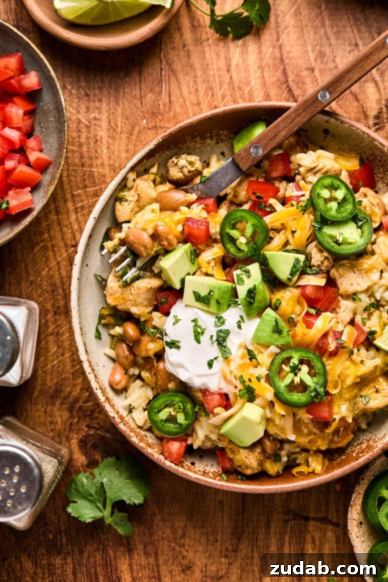 a photo of a bowl of cilantro lime chicken burrito bowl topped with melted cheese, sour cream and sliced jalapenos