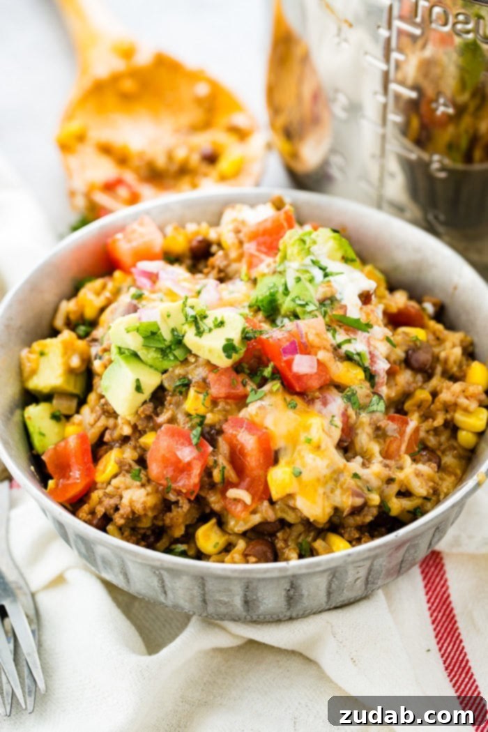 Instant Pot Ground Beef Burrito Bowls in Minutes 6 A top-down view of an Instant Pot Ground Beef Burrito Bowl, beautifully arranged with seasoned ground beef, rice, black beans, and an assortment of fresh toppings including chopped tomatoes, creamy avocado, and vibrant cilantro.