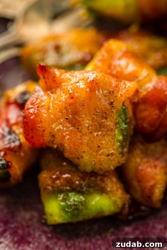 Crispy Bacon Avocado Bites 3 Brown sugar bacon wrapped around a piece of avocado and baked until crispy is sitting on a pile of the bacon wrapped avocados