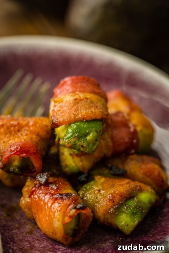 Crispy Bacon Avocado Bites 5 Bacon wrapped around pieces of green avocados with brown sugar and baked until crispy, all piled up on a plate as an easy appetizer recipe