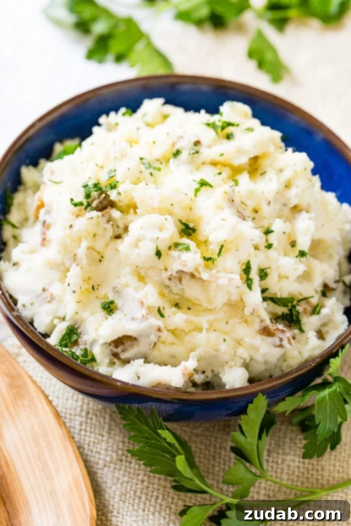Crispy Garlic Smashed Potatoes 3 A close-up shot of a blue ceramic bowl overflowing with chunky, rustic smashed potatoes, generously topped with fresh chopped parsley.