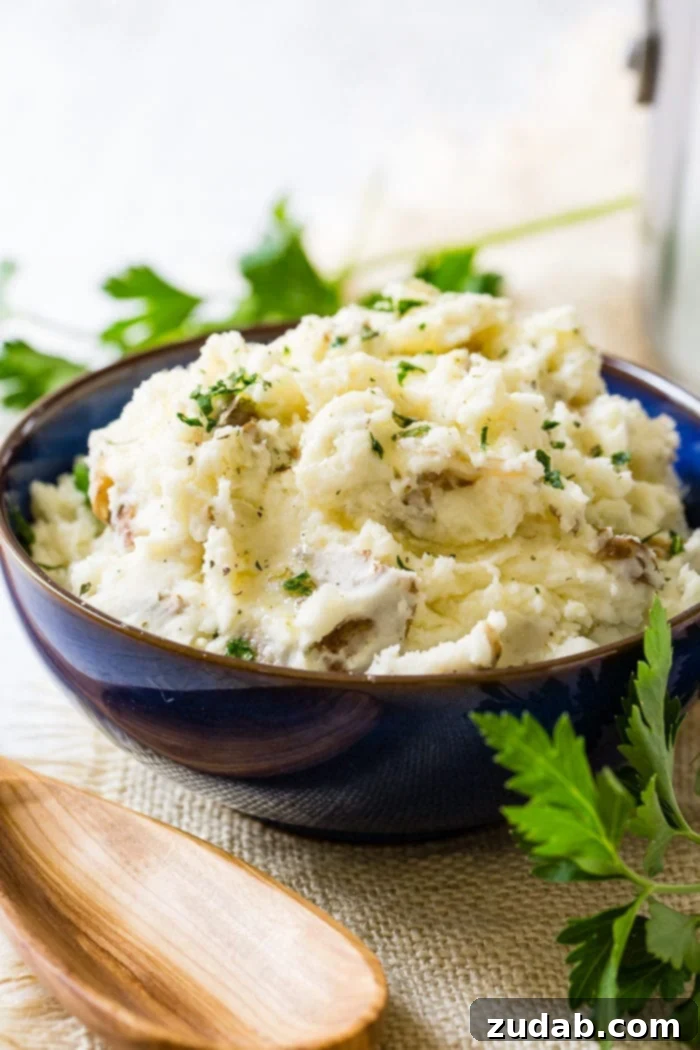 Crispy Garlic Smashed Potatoes 4 A beautiful wide shot of a blue serving bowl filled with creamy, chunky smashed potatoes, garnished with vibrant fresh parsley, ready to be served.