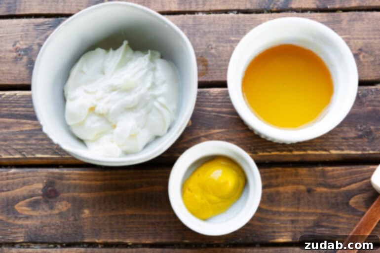 Simple Sauces That Make Ham Shine 4 A perfectly composed overhead shot featuring the three essential ingredients for honey mustard dipping sauce—creamy mayonnaise, golden honey, and classic yellow mustard—each presented in individual small bowls.