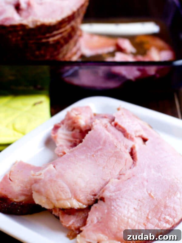 Pieces of ham on a dinner plate with a spiral ham in the background