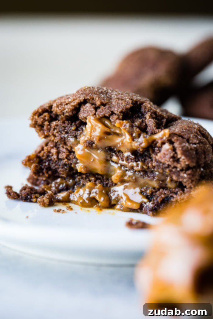 Dulce De Leche-Filled Mexican Chocolate Delights 4 A close-up of three halved Dulce de Leche Stuffed Chocolate Mexican Cookies, prominently displaying the rich, flowing caramel filling. The warm, inviting colors hint at the deliciousness within.